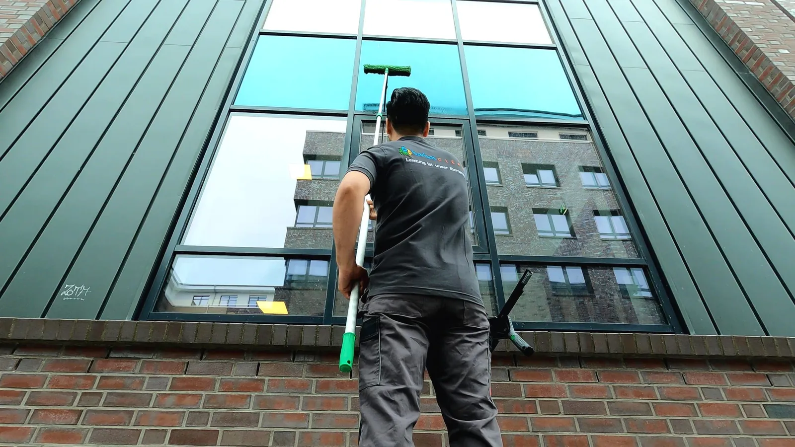 Glasreinigung: Mitarbeiter reinigt eine große Fensterfront an einer Fassade