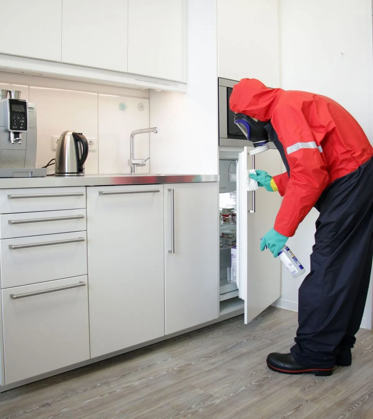 Desinfektion: Mitarbeiter in Schutzanzug desinfiziert in einer Teeküche