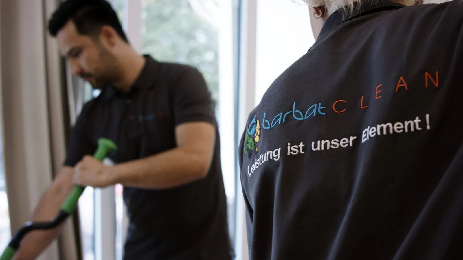 Reinigungsdienst: Mitarbeiter bei der Arbeit, im Vordergrund das Barbat-Clean-Logo auf der Dienstkleidung