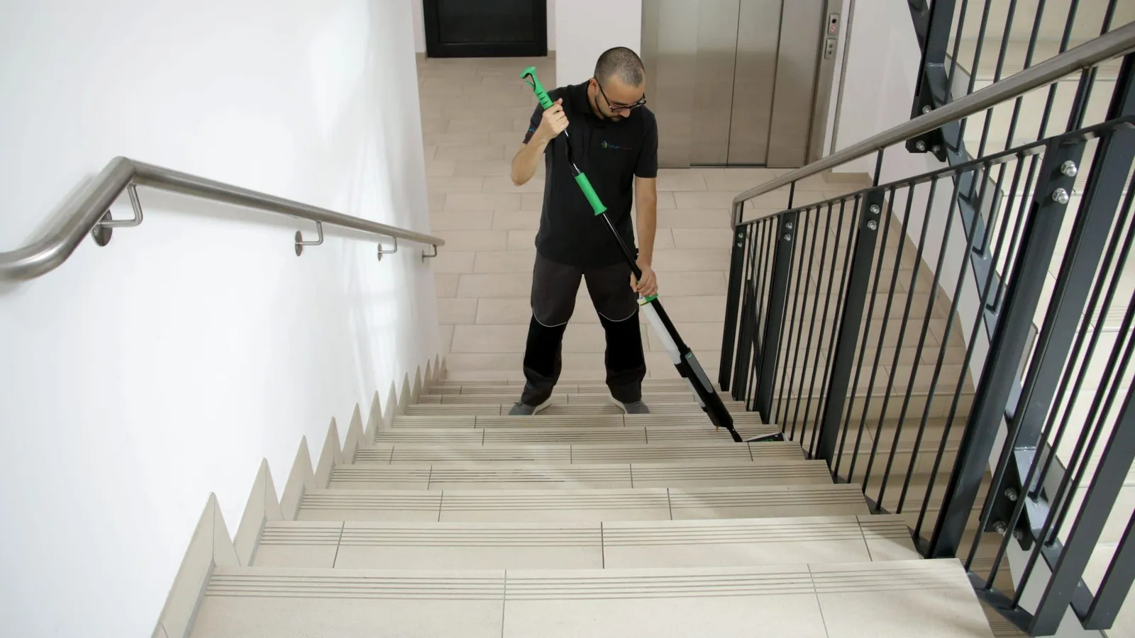 Treppenhausreinigung: Mitarbeiter wischt Treppenstufen im Treppenhaus