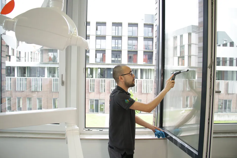 Barbat-Clean-Mitarbeiter zieht ein Fenster mit dem Abzieher ab