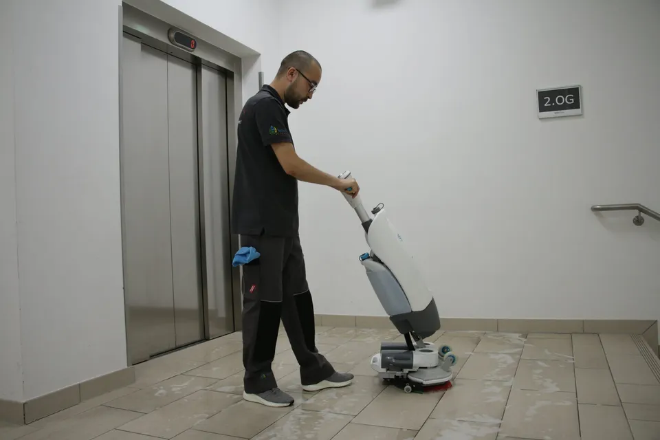 Barbat-Clean-Mitarbeiter reinigt den Boden im Treppenhaus mit einer Scheuersaugmaschine